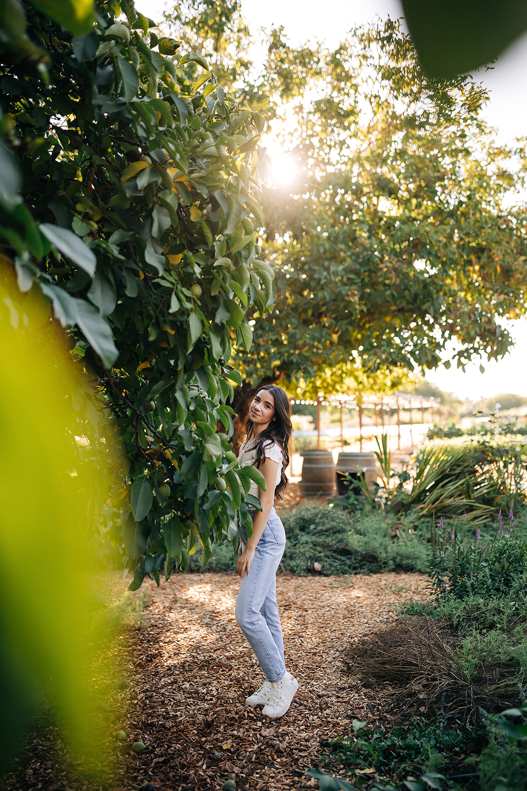 a girl standing behind a tree posing