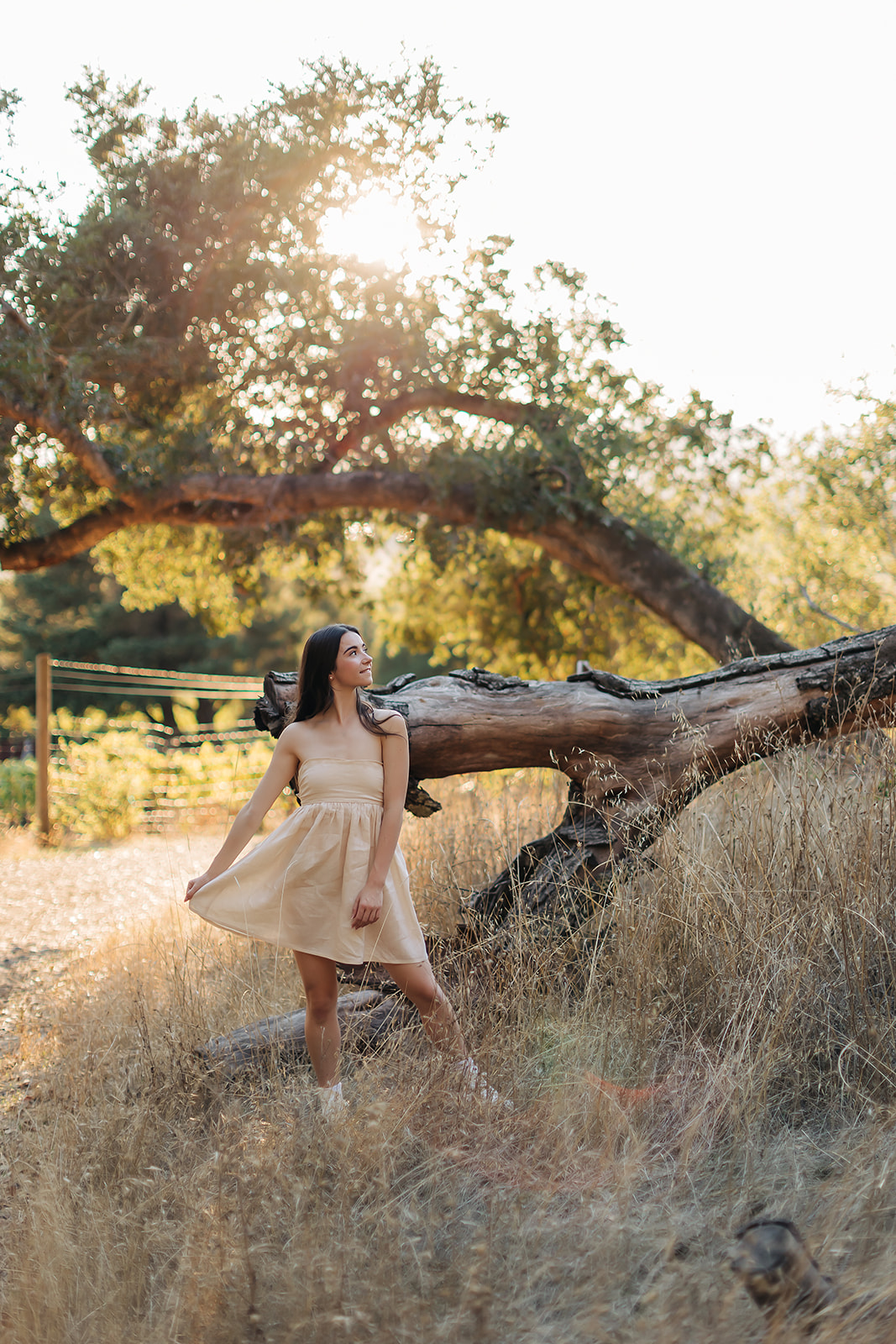 a girl standing in front of a fallen tree posing